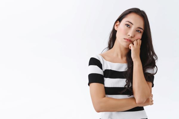 bored young asian woman looking into distance with unamused sad expression lean face fist pull grimace annoyed standing uninterested meeting white background thinking pensive